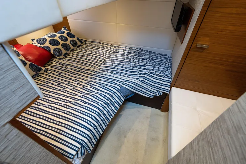Slide: The Image of Cozy cabin interior of 2015 Tiara Yachts C44 Coupe with striped bedding and wooden accents. - 31