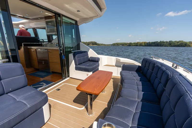 Slide: The Image of 2015 Tiara Yachts C44 Coupe interior with blue seating, wooden table, and scenic water view. - 38