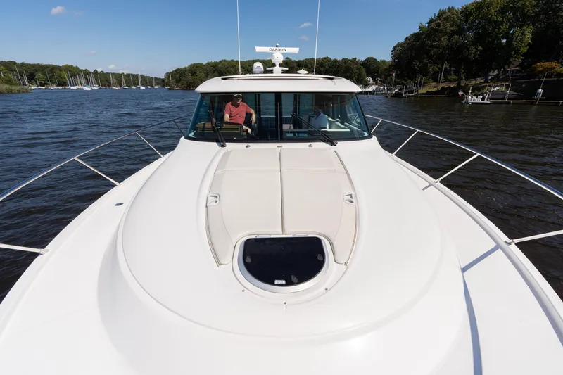 Slide: The Image of 2015 Tiara Yachts C44 Coupe cruising on a scenic river under a clear blue sky. - 46