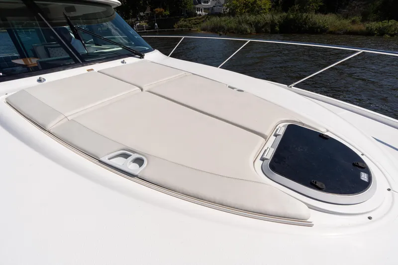 Slide: The Image of 2015 Tiara Yachts C44 Coupe deck with sunpad and hatch, docked by the water. - 47