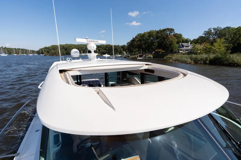 Slide: The Image of 2015 Tiara Yachts C44 Coupe cruising on a scenic river under a clear blue sky. - 48