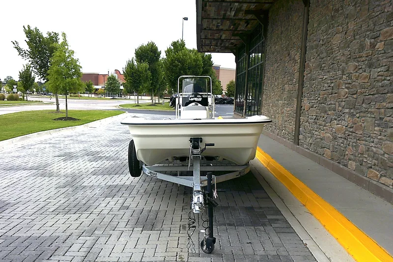 Slide: The Image of 2026 Mako Pro Skiff 17 CC boat on trailer, parked near stone building. - 2