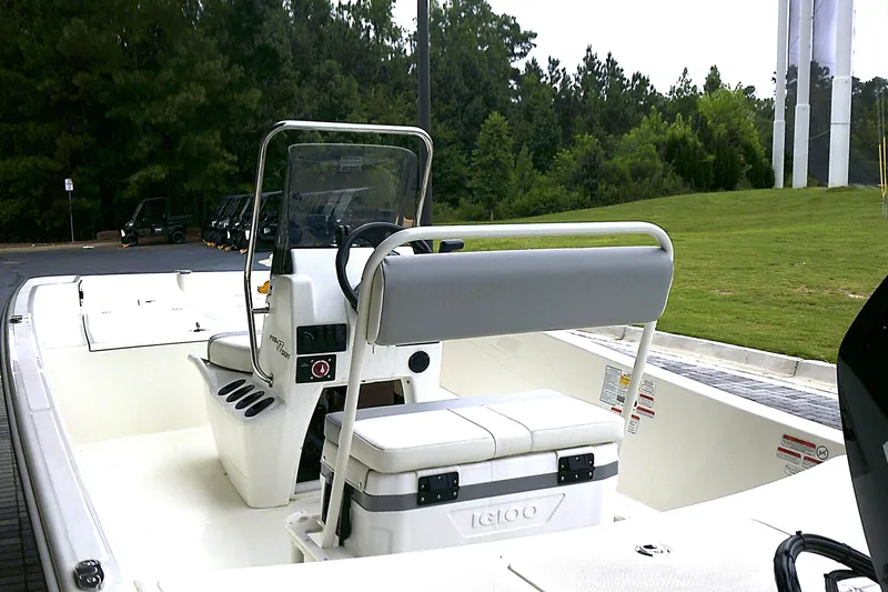 Slide: The Image of 2026 Mako Pro Skiff 17 CC boat with center console and seating, parked near greenery. - 4