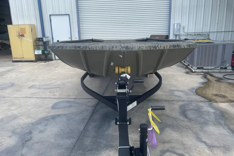 Slide: The Image of 2026 Tracker Grizzly 1860 Utility boat on trailer in industrial setting. - 2