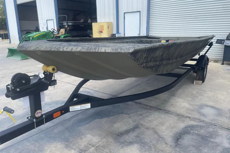 Slide: The Image of 2026 Tracker Grizzly 1860 Utility boat on trailer, parked outside a warehouse. - 3