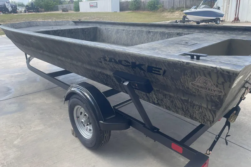 Slide: The Image of 2026 Tracker Grizzly 1860 Utility boat on trailer, camo design, parked outdoors. - 4