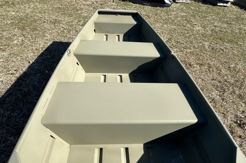 Slide: The Image of 2026 Tracker Grizzly 10 Jon boat interior with bench seats on grass. - 1