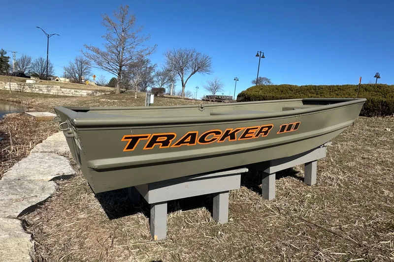 Slide: The Image of 2026 Tracker Grizzly 10 Jon boat displayed outdoors on a sunny day. - 2