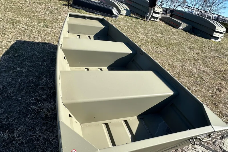Slide: The Image of 2026 Tracker Grizzly 10 Jon boat on grassy field, showcasing interior seating. - 3