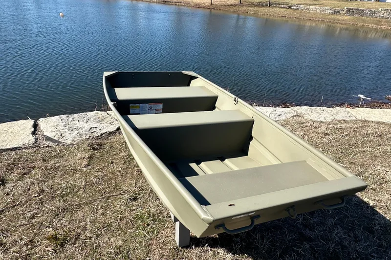 Slide: The Image of 2026 Tracker Grizzly 10 Jon boat by a serene lakeside. - 5