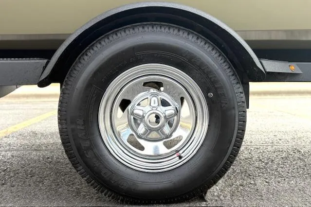 Slide: The Image of 2026 Tracker Pro Team 190 trailer wheel with chrome rim on asphalt surface. - 28