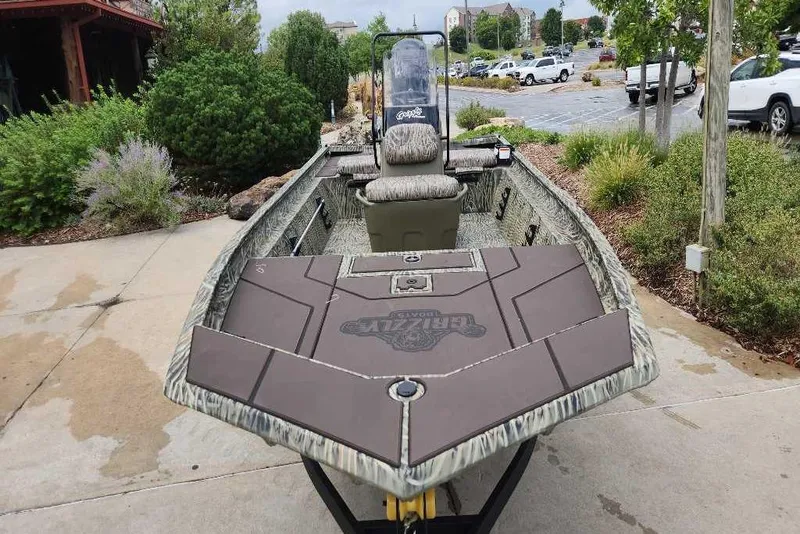 Slide: The Image of 2026 Tracker Grizzly 1860 CC boat on display, surrounded by greenery and parked cars. - 69