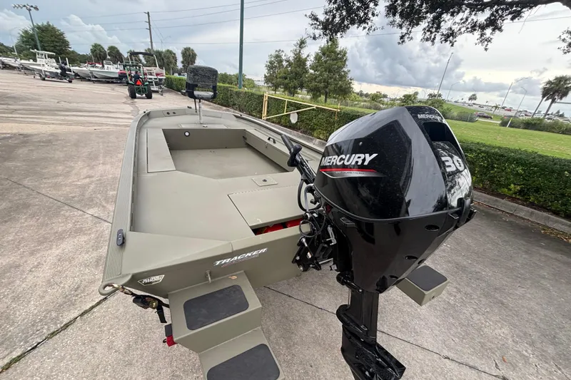 Slide: The Image of 2026 Tracker Grizzly 1654 T Sportsman boat with Mercury 30 outboard motor, parked outdoors. - 2