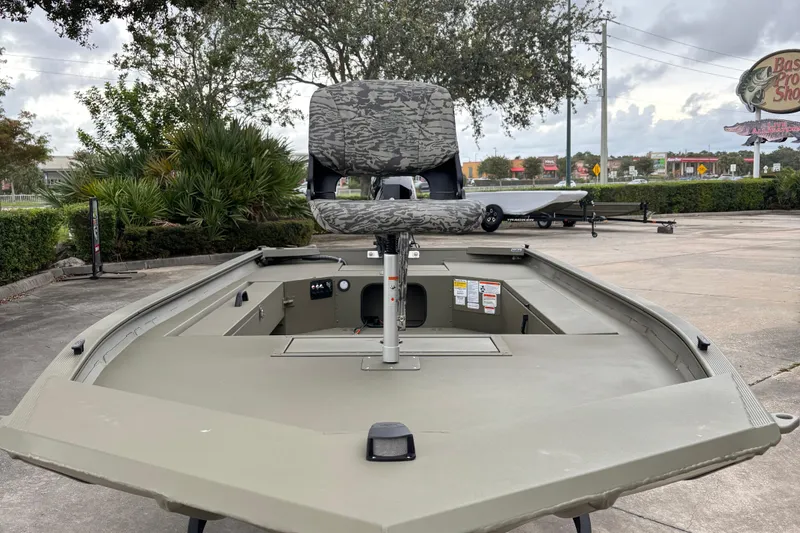 Slide: The Image of 2026 Tracker Grizzly 1654 T Sportsman boat with camo seat, parked outdoors. - 3
