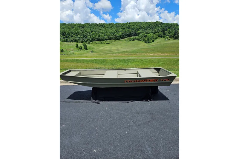 Slide: The Image of 2026 Tracker Grizzly 12 Jon boat on pavement with scenic green hills background. - 1