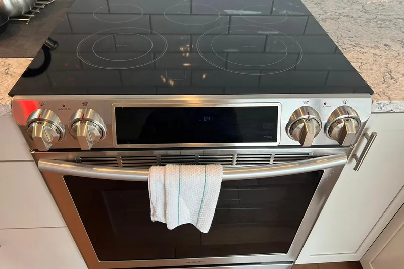 Slide: The Image of Modern stainless steel electric stove with digital display and towel on handle. - 11