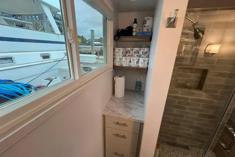 Slide: The Image of 1981 Sumerset houseboat bathroom with shower, storage shelves, and marina view. - 21