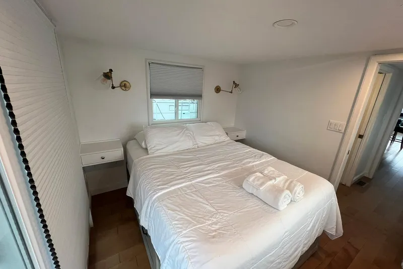 Slide: The Image of Cozy bedroom in 1981 Sumerset houseboat with white bedding and wall-mounted lamps. - 23