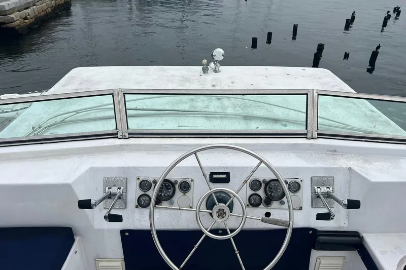 Slide: The Image of 1981 Sumerset houseboat helm with steering wheel and control panel on calm water. - 29