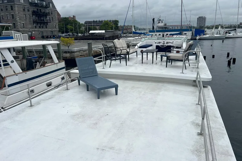 Slide: The Image of 1981 Sumerset Houseboat with deck chairs, docked in a marina, overcast sky. - 32