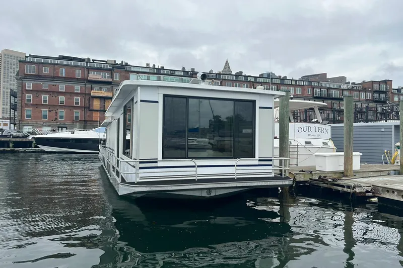 Slide: The Image of 1981 Sumerset houseboat docked in a marina, with urban buildings in the background. - 34