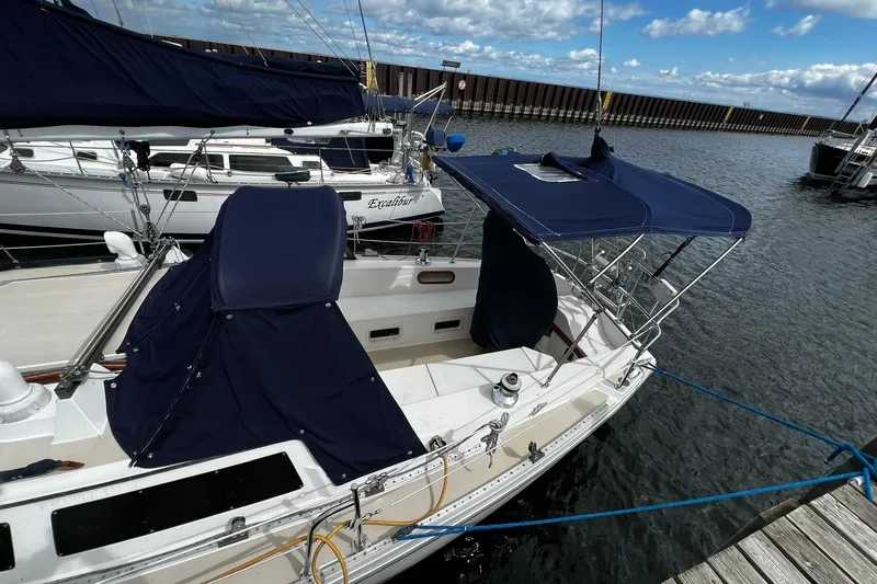 Slide: The Image of 1988 Catalina 34 sailboat docked, featuring blue canvas covers and a spacious deck area. - 10