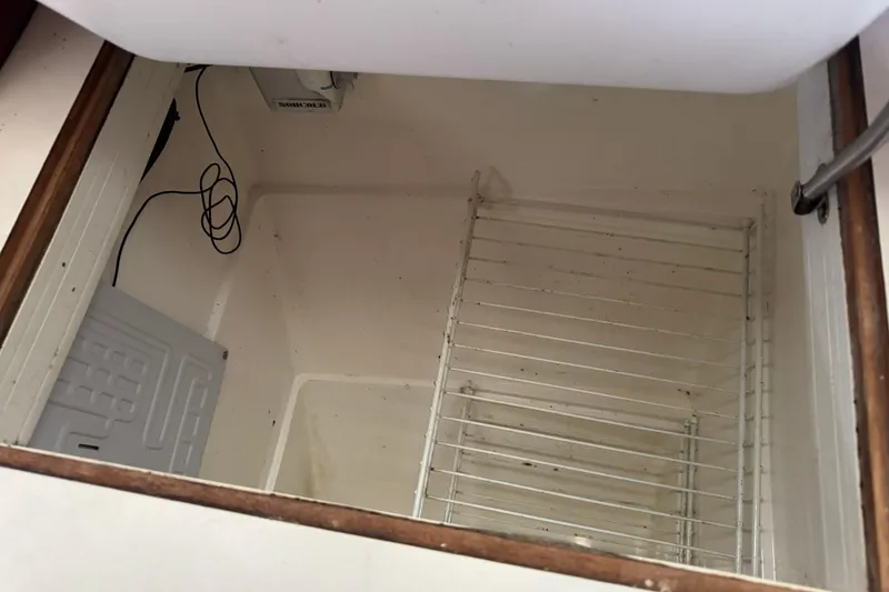 Slide: The Image of Empty storage compartment in a 1988 Catalina 34 sailboat, featuring wire rack shelving. - 16