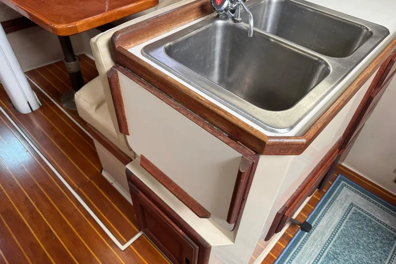 Slide: The Image of 1988 Catalina 34 yacht interior with wooden flooring and dual stainless steel sink. - 18