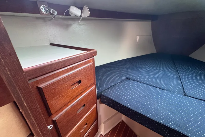 Slide: The Image of Cozy cabin interior of 1988 Catalina 34 sailboat with wooden drawers and blue bedding. - 29