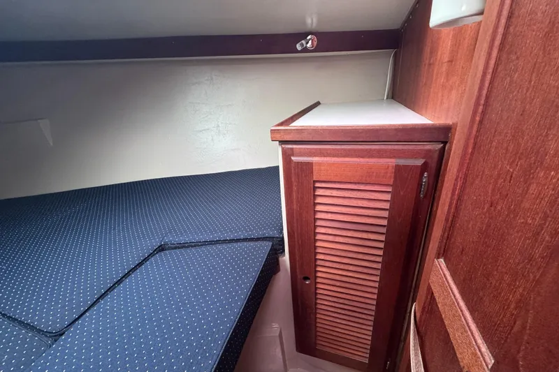 Slide: The Image of 1988 Catalina 34 interior cabin with wooden cabinet and blue cushioned bed. - 30