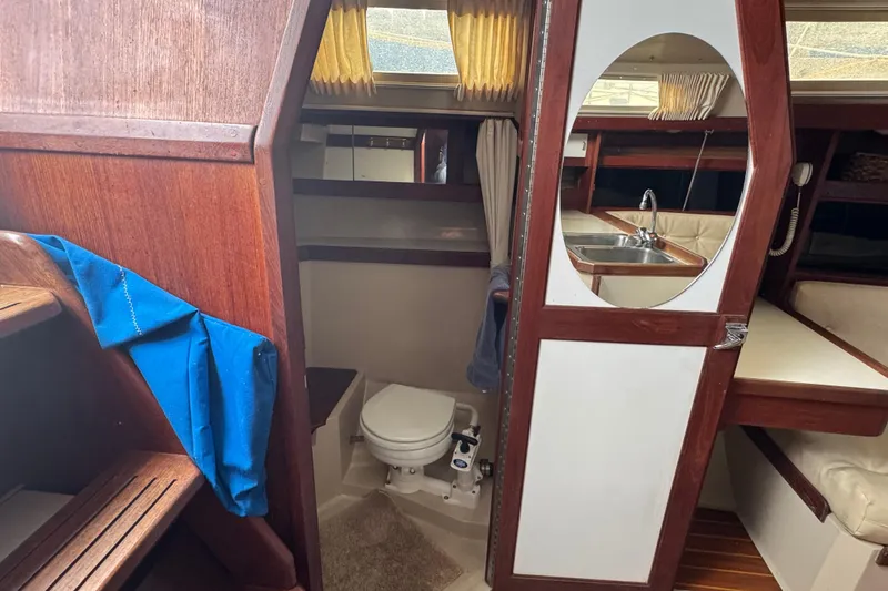 Slide: The Image of 1988 Catalina 34 yacht interior with wooden finish, showing bathroom and kitchenette. - 35