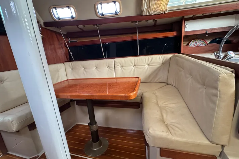 Slide: The Image of Interior of 1988 Catalina 34 sailboat with cushioned seating and wooden table. - 36