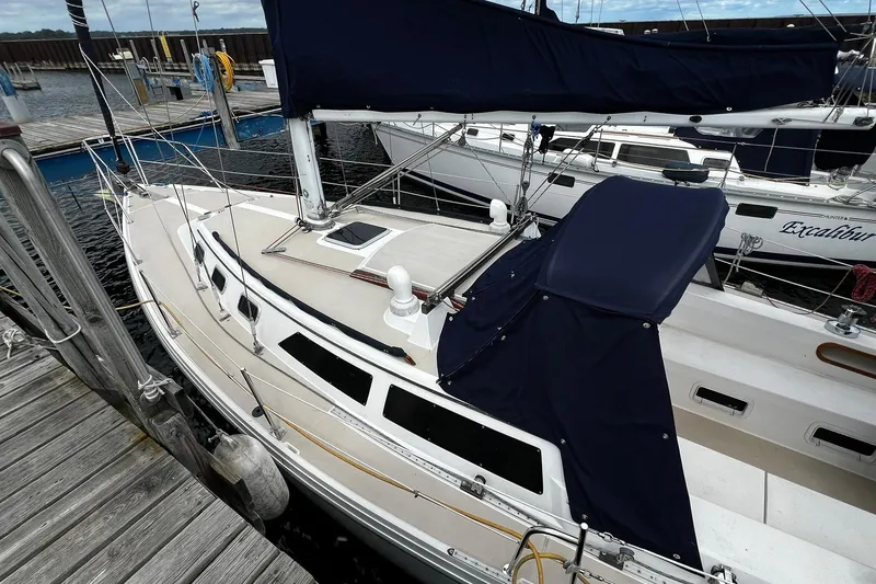 Slide: The Image of 1988 Catalina 34 sailboat docked at marina, featuring blue covers and sleek design. - 4