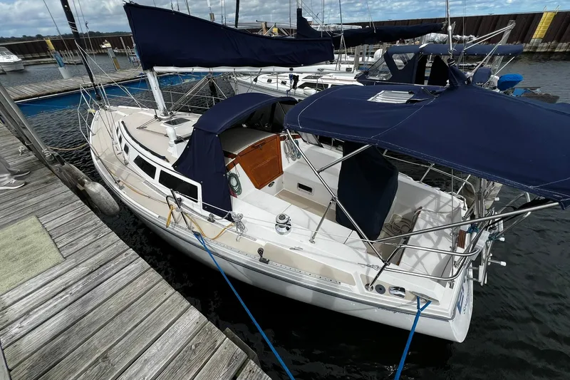 Slide: The Image of 1988 Catalina 34 sailboat docked, featuring blue canvas covers and sleek white design. - 5