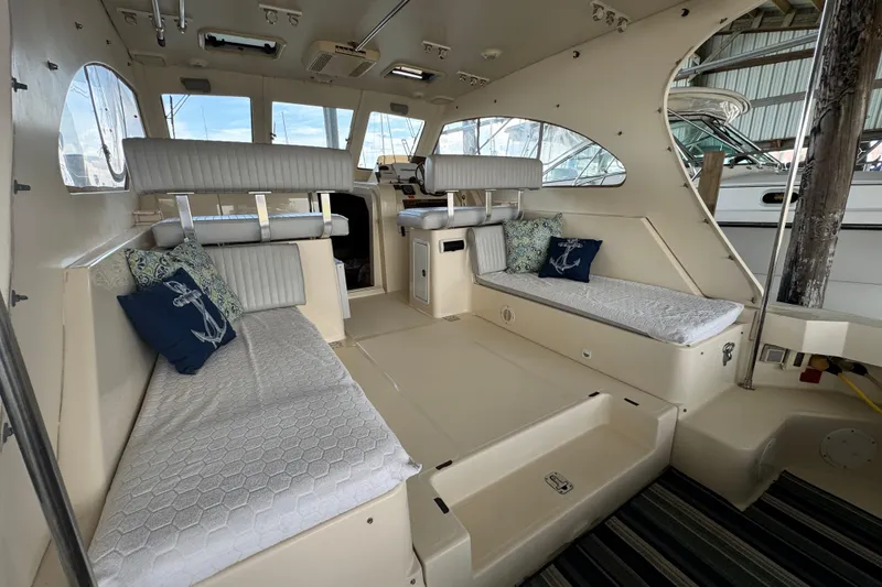 Slide: The Image of 2003 Mainship Pilot 34 interior with cushioned seating and nautical-themed pillows. - 14