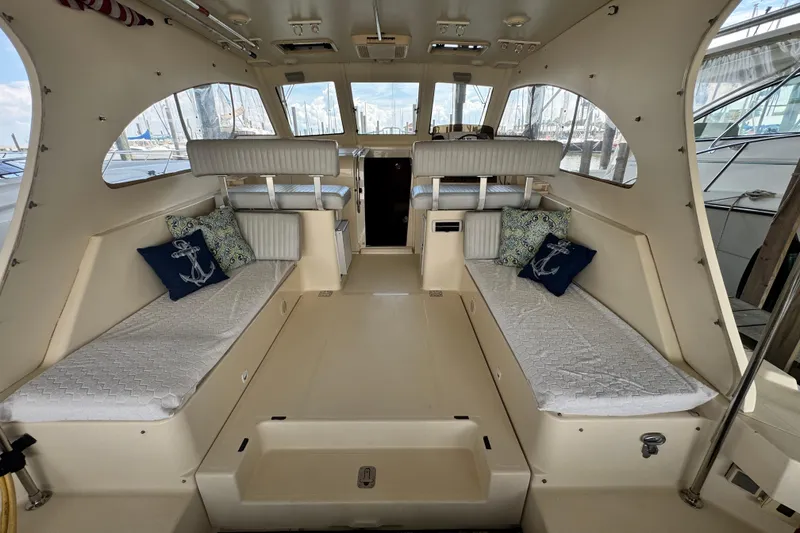 Slide: The Image of 2003 Mainship Pilot 34 interior with cushioned seating and nautical-themed pillows. - 15