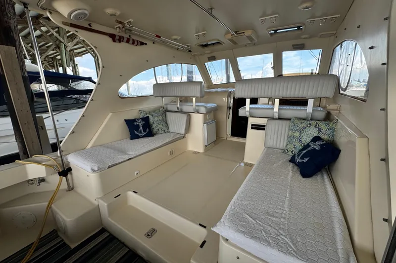 Slide: The Image of 2003 Mainship Pilot 34 interior with cushioned seating and nautical-themed pillows. - 16