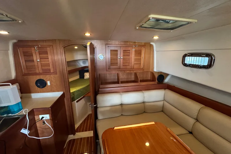 Slide: The Image of 2003 Mainship Pilot 34 interior with wood cabinetry, cozy seating, and a compact kitchenette. - 18