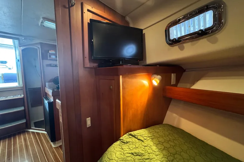 Slide: The Image of 2003 Mainship Pilot 34 cabin interior with TV, bed, and wooden furnishings. - 30