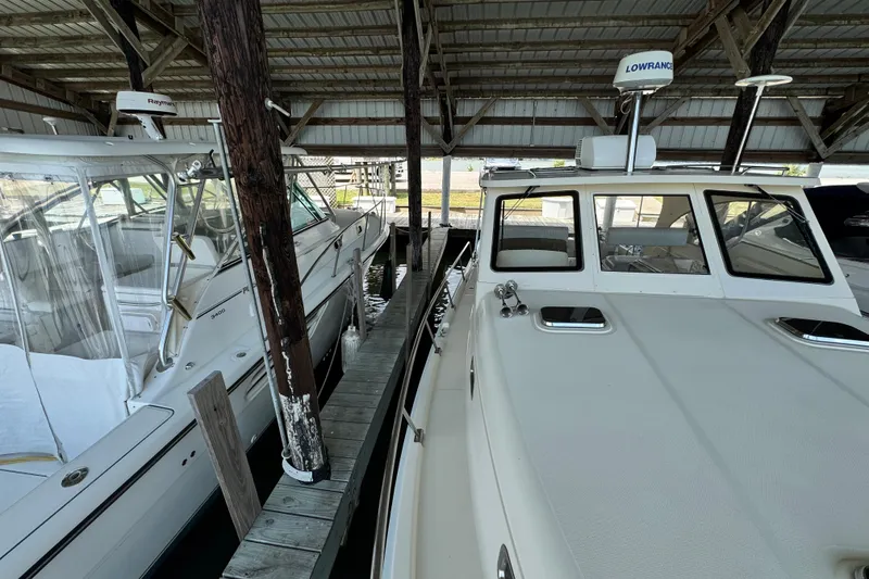 Slide: The Image of 2003 Mainship Pilot 34 docked under a covered marina, showcasing its sleek design. - 5