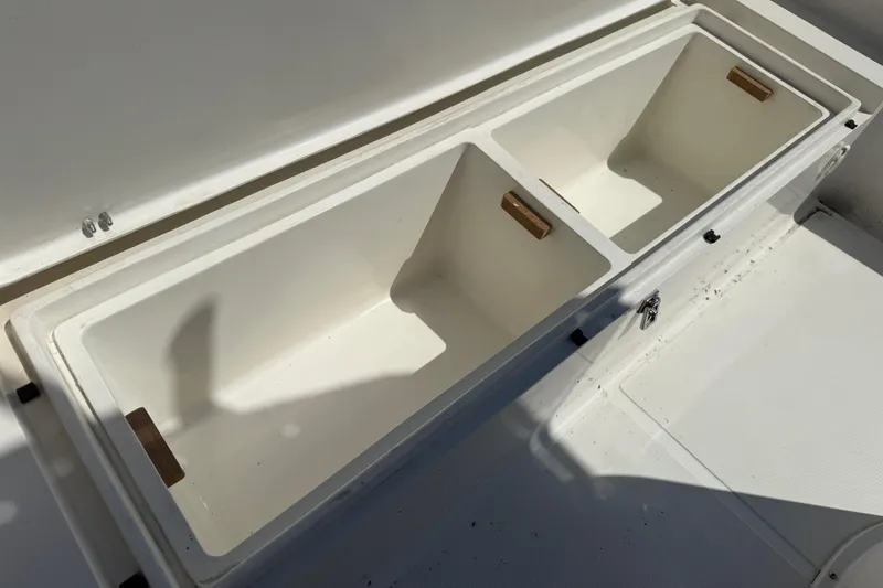 Slide: The Image of 2023 Banks Panga 23 Center Console storage compartments, open and empty, in bright sunlight. - 15