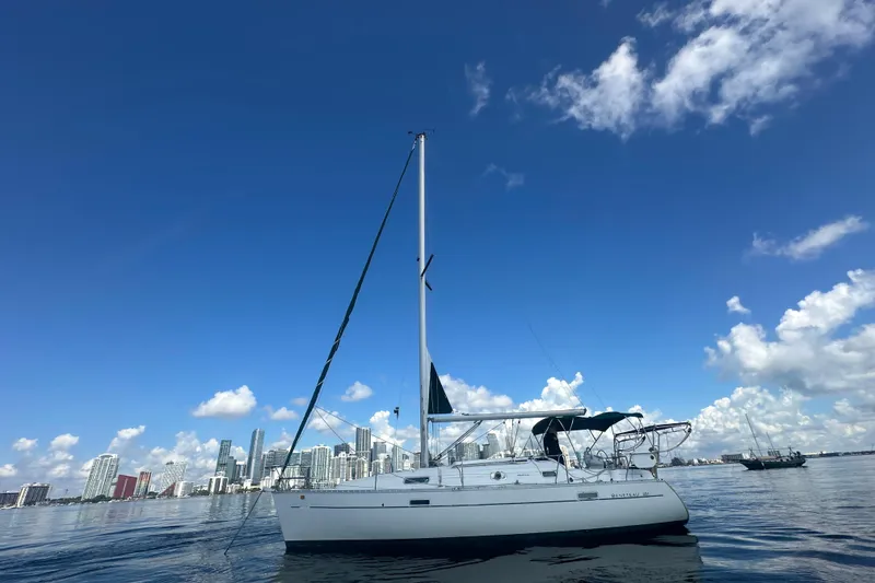 The Image of 2003 Beneteau Oceanis Clipper 331 sailboat on calm water with city skyline background. - 0