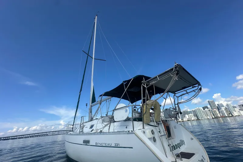 Slide: The Image of 2003 Beneteau Oceanis Clipper 331 sailboat on calm water with city skyline backdrop. - 12