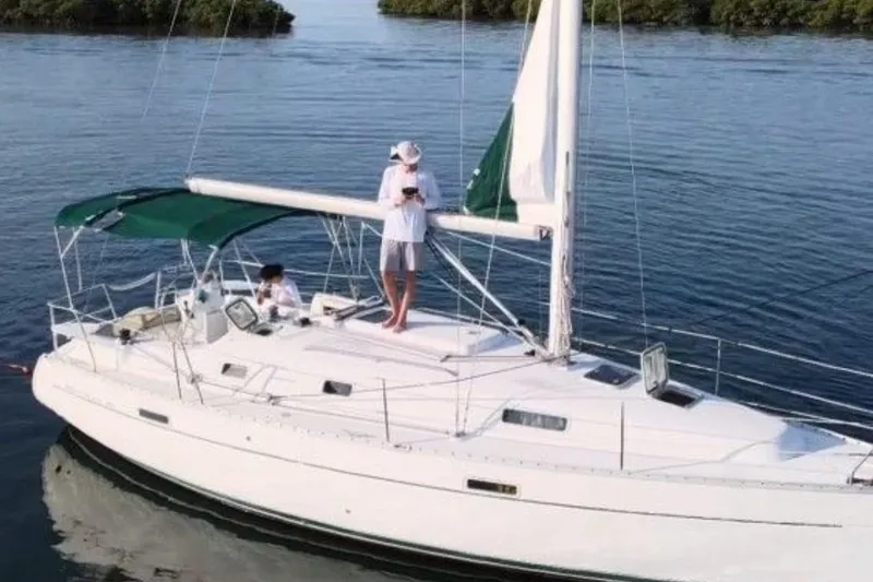 Slide: The Image of 2003 Beneteau Oceanis Clipper 331 sailboat on calm water, featuring green canopy. - 2