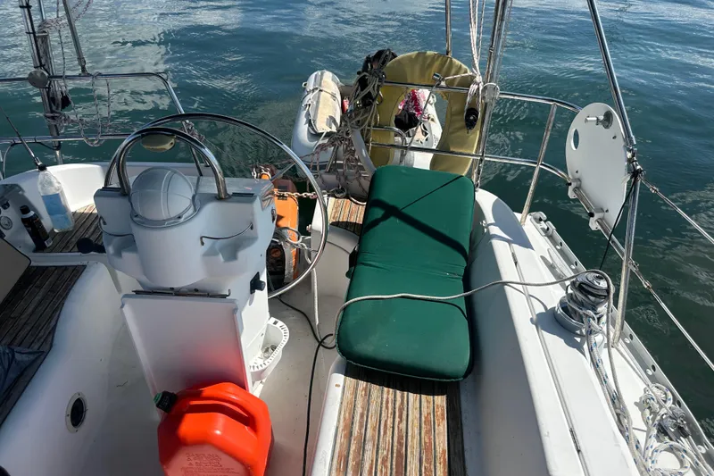 Slide: The Image of 2003 Beneteau Oceanis Clipper 331 sailboat cockpit with steering wheel and green cushion. - 29