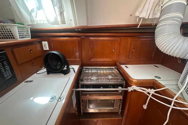 Slide: The Image of 2003 Beneteau Oceanis Clipper 331 yacht kitchen with stove and wooden cabinetry. - 38