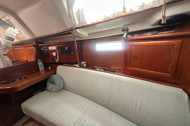Slide: The Image of 2003 Beneteau Oceanis Clipper 331 interior with wooden cabinetry and cushioned seating. - 46
