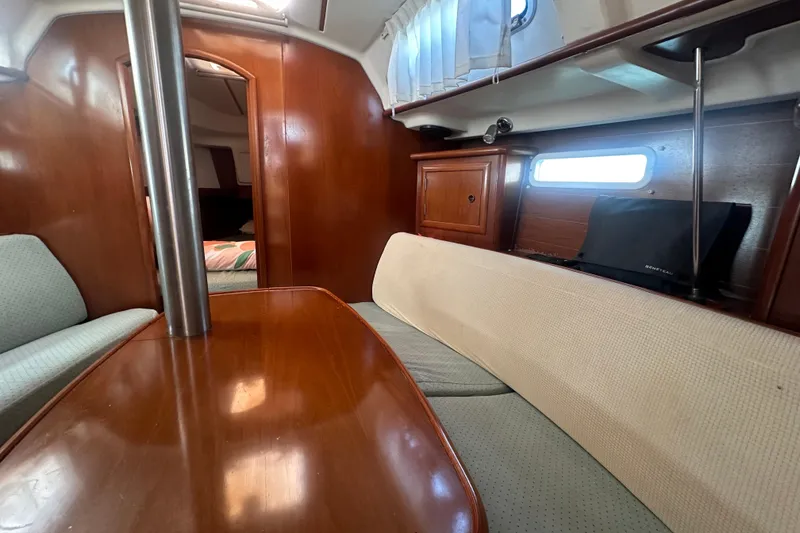 Slide: The Image of Interior of 2003 Beneteau Oceanis Clipper 331 sailboat, featuring cozy seating and wooden finishes. - 54