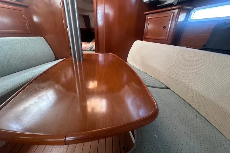 Slide: The Image of Interior of 2003 Beneteau Oceanis Clipper 331, featuring wooden table and cushioned seating. - 55