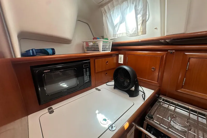 Slide: The Image of 2003 Beneteau Oceanis Clipper 331 galley with microwave, fan, and wooden cabinetry. - 58